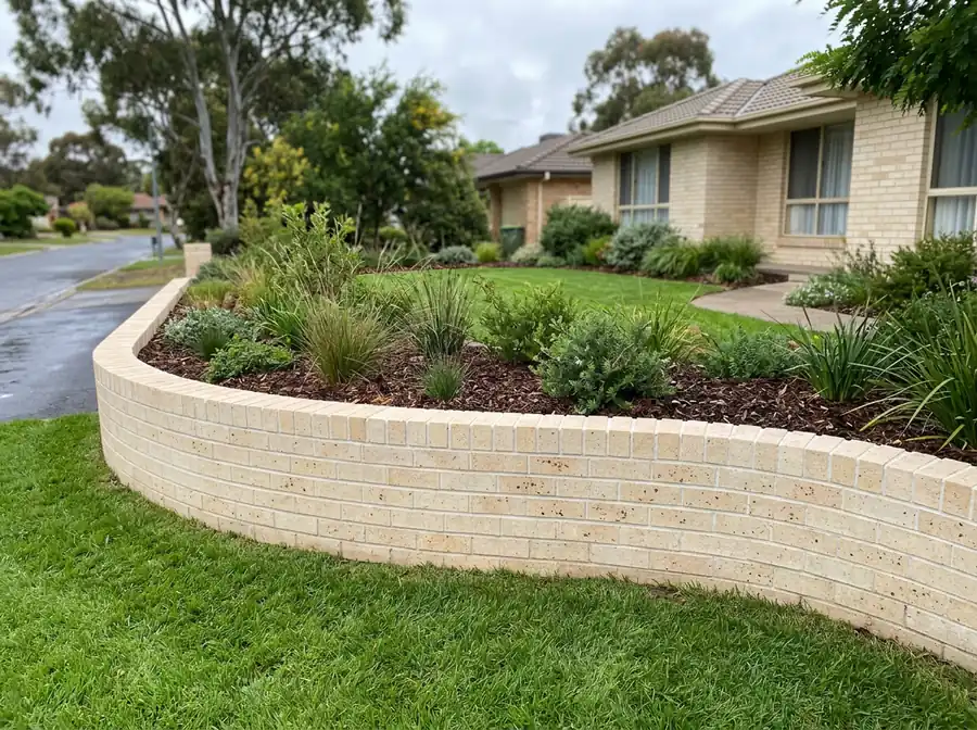 A curved cream brick garden wall with a brick on edge capping course